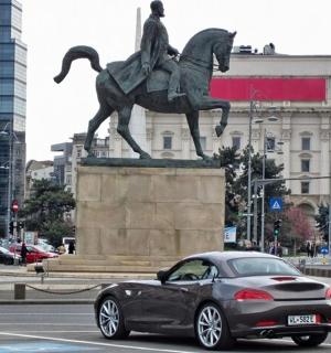 一辆汽车驶过一座骑马男子的雕像
