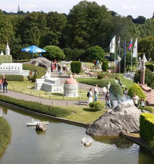 lidé procházející se po zahradě s loděmi ve vodě