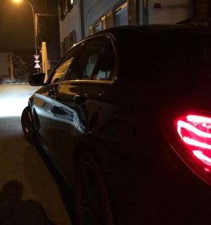 a car with a red tail light on a street at night