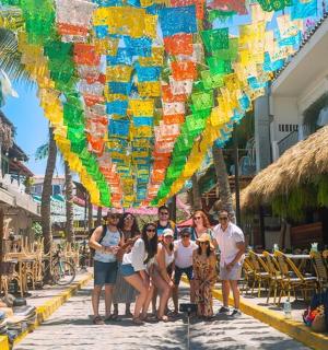 a group of people standing on a street under a colorful umbrella