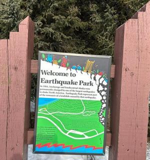 a sign on a fence at a park in the snow