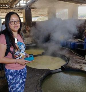 一名妇女站在一锅食物前
