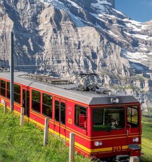 ein roter Zug auf einem Hügel mit einem Berg