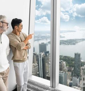 two men standing in front of a window looking at the city