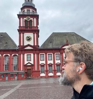 Ein Mann steht vor einem großen Gebäude mit einem Uhrenturm