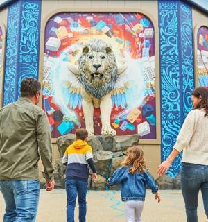 a family walking in front of a mural of a lion