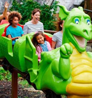 a group of children riding on a toy train at a park