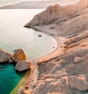 一片有岩石的海滩，水中有一艘船