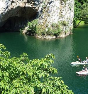 two people on boats in a river with a cave