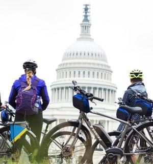 skupina lidí stojících s koly před budovou hlavního města