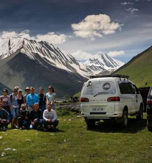 a group of people standing in a field next to two vans