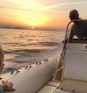 two men in a boat on the water at sunset