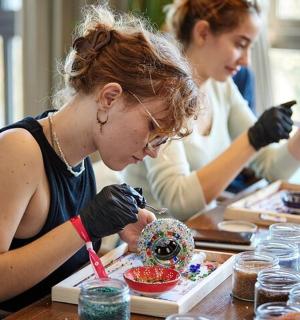two women sitting at a table working on a project