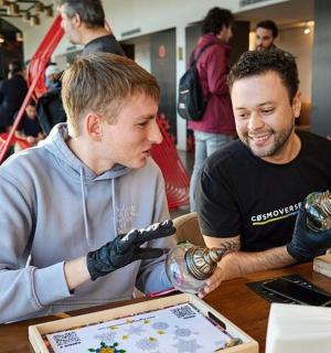 a couple of men sitting at a table with gloves