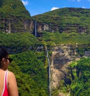 一名女子站在悬崖上，看着瀑布