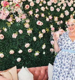 一位女士站在花墙前