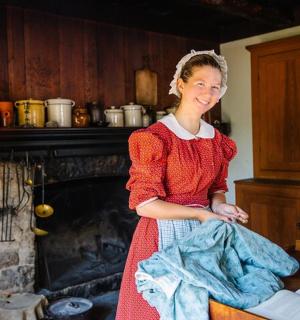 a woman in a red dress standing in front of a fireplace