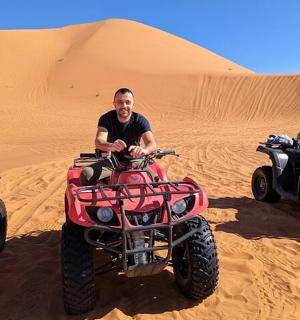 a man standing in the desert with two atvs