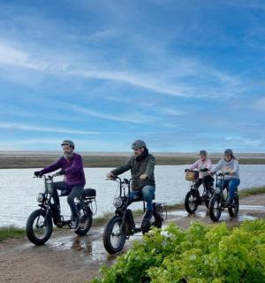 three people riding bikes on a path by the water