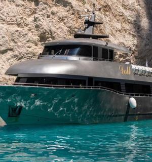 a boat in the water next to a cliff