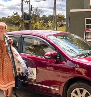 a man and a woman standing next to a red car