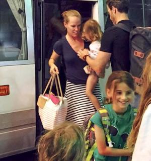 a woman holding a child standing next to a bus