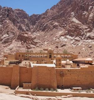 a building in the middle of a desert with a mountain