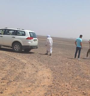 a group of people standing next to a car in the desert