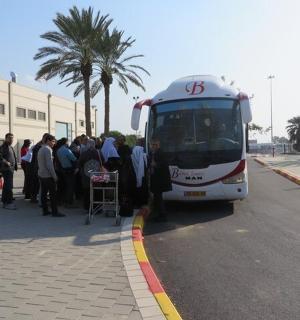 skupina lidí čekajících na nástup do autobusu