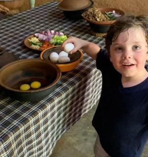 一个小男孩站在一张放着鸡蛋的桌子前