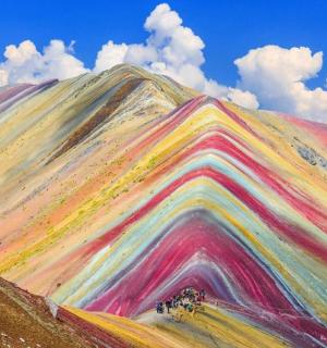 Duhově zbarvená hora s lidmi stojícími kolem ní