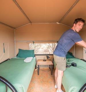 一名男子站在有两张床的帐篷里