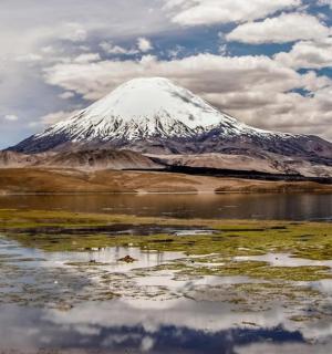 a snow covered mountain with a reflection in a body of water