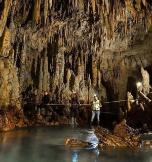 a group of people standing in the water in a cave