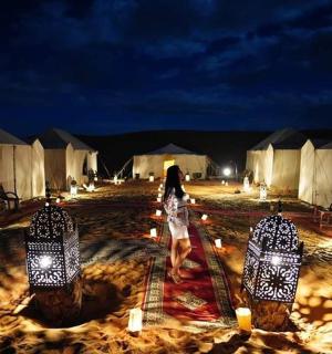 Žena v noci prochází skupinou stanů