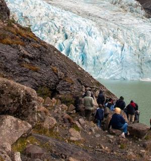 a group of people on a mountain looking at a glacier