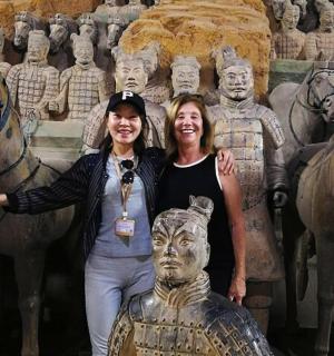 two women standing next to a statue in front of a museum