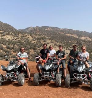 a group of people sitting on four wheelers in the desert