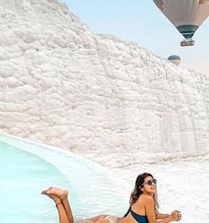 a woman sitting on the beach with hot air balloons