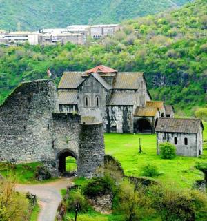 an old building on a green field with a mountain