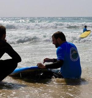 两个人坐在海里，手里拿着冲浪板