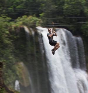 muž jedoucí na zipline přes vodopád