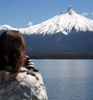 a woman looking at a snow covered mountain over a lake
