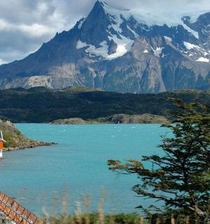 a house on the shore of a lake in front of a mountain