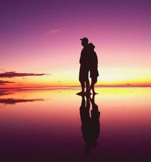 a man standing on the beach watching the sunset