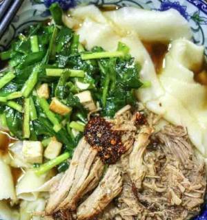 a blue and white bowl of food with meat and vegetables