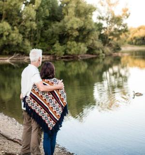 a man and woman standing by a lake with a dog