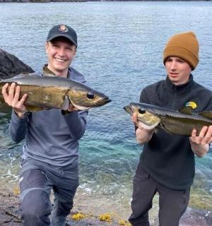 dva muži držící rybu ve vodě