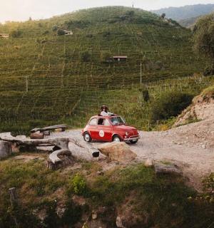 a man driving a small red car on a hill