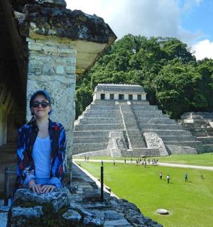 一位女士坐在金字塔前的墙上